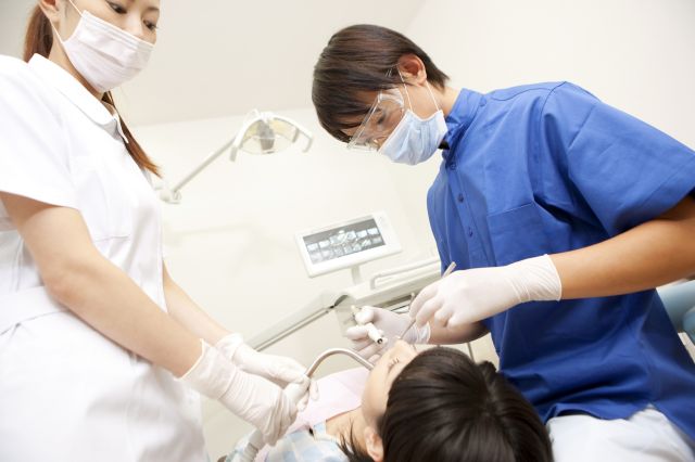 歯周病治療を行う歯科医師と女性歯科スタッフ